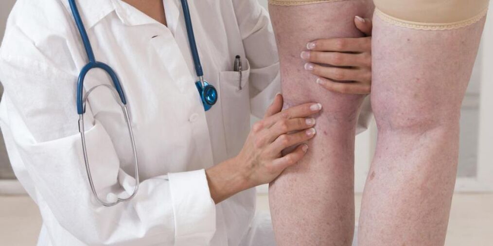 El médico examina las piernas del paciente